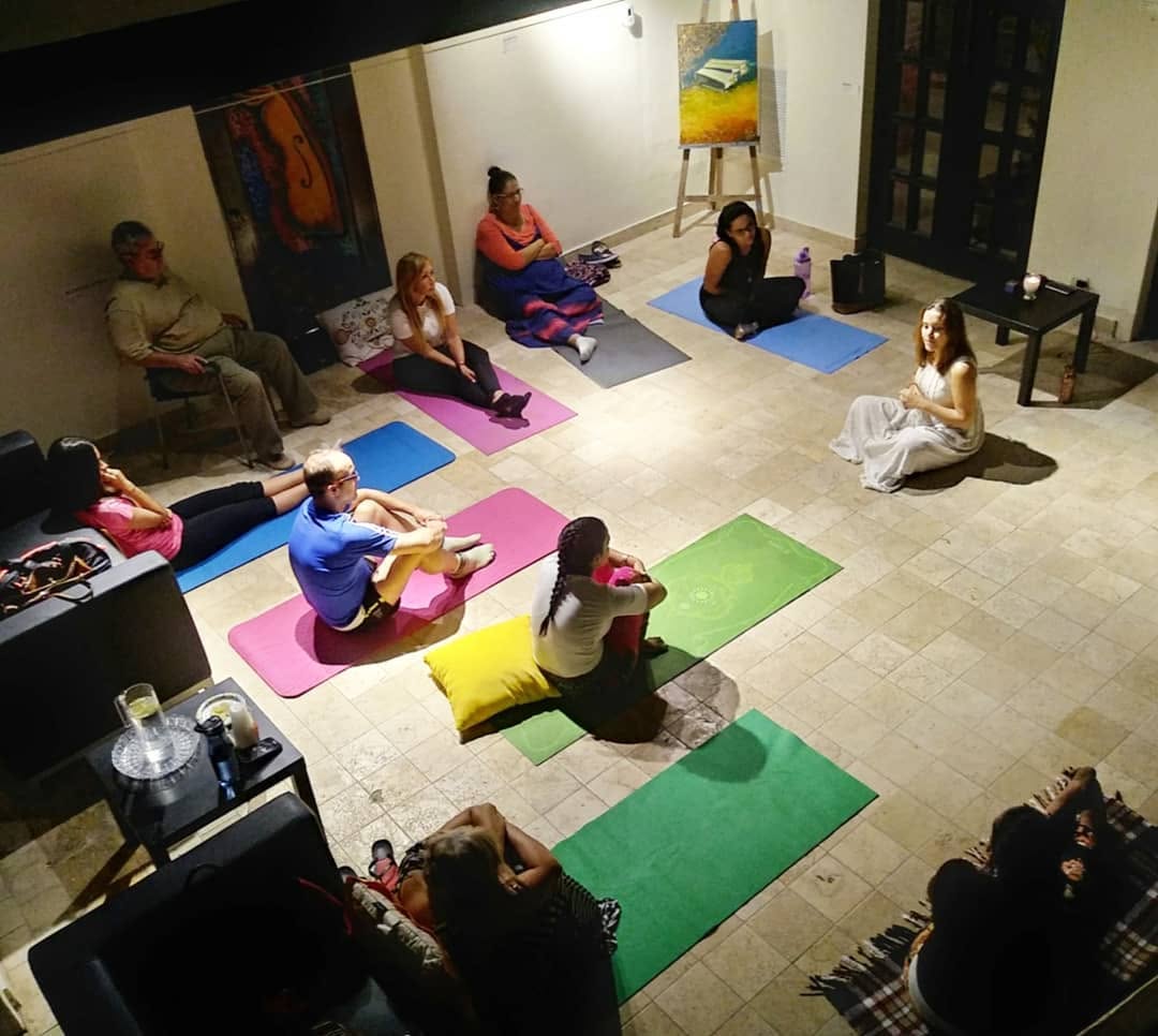 Participantes adultos en esterillas de yoga durante el Happiness Program en la Academia